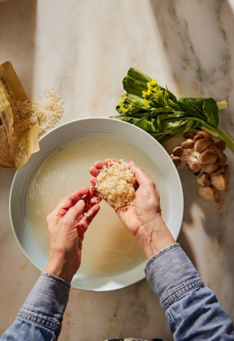 Hands washing Tamaki Haiga Rice in a bowl of water
