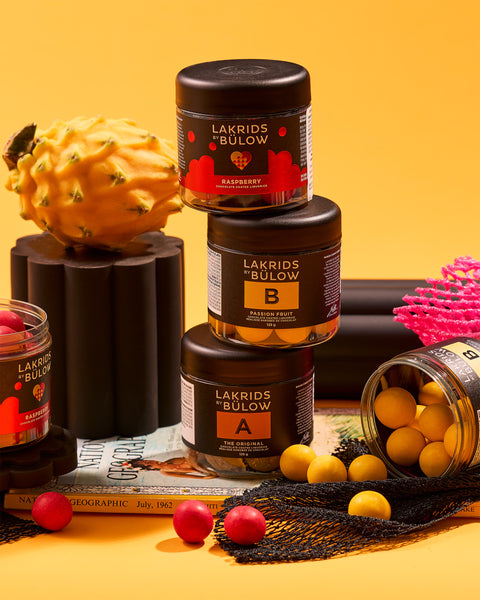 Passionfruit, Original and Raspberry Lakrids by Bulow on a yellow surface