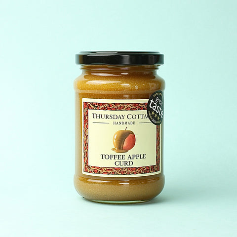 A jar of Thursday Cottage Toffee Apple Curd on a blue background