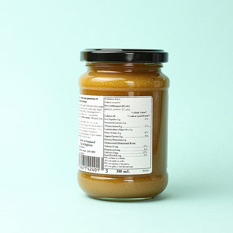 A jar of Thursday Cottage Toffee Apple Curd on a blue background turned to show Nutritional Information